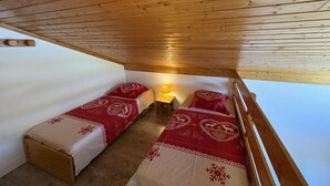 Una habitación pequeña y acogedora con dos camas, una mesita de noche y una lámpara.