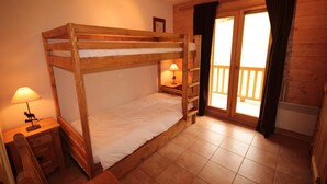 A wooden bunk bed room with a window and a nightstand with a lamp. - 200m from shops, 1st floor, swimming pool, balcony, tv, 46m², Les Saisies (Villard-sur-Doron)