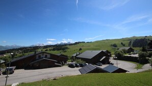 Un pittoresco villaggio rurale con case tradizionali, cielo sereno e montagne sullo sfondo.