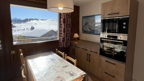 Cucina con pensili e basi in legno, forno integrato e zona pranzo con tavolo e sedie.