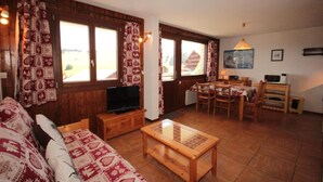 Un accogliente soggiorno con un divano in legno, una TV e un'area pranzo con tavolo e sedie.