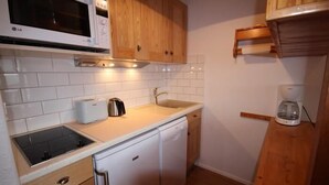 Ett kompakt kök med vita skåp, en mikrovågsugn, en brödrost och en kaffebryggare.