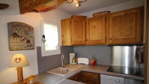 A compact kitchen with wooden cabinets, a sink, a toaster, a coffee maker, and a dishwasher. - 300m from ski slopes, Ground floor, view mountain, balcony, tv, 28m², Les Saisies (Les Saisies)