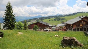 A mountain village with wooden buildings, a clear sky, and a view of snow-capped mountains in the background. - 300m from ski slopes, Ground floor, view mountain, balcony, tv, 28m², Les Saisies (Les Saisies)