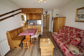 Un espace de vie accueillant et compact, comprenant un banc en bois, une table à manger et un canapé à motifs.