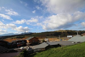 Un pittoresco borgo rurale con case in legno tradizionali, una strada pavimentata e montagne sullo sfondo.