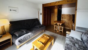 A cozy living room with a sofa, a wooden coffee table, and a dining area with a table and chairs. - 100m from ski slopes, 1st floor, view ski slopes, balcony, tv, ski locker, 23m², Les Saisies (Les Saisies)