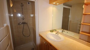 Een badkamer met een douche met glazen wanden, een wastafel met spiegel en een wasbak.