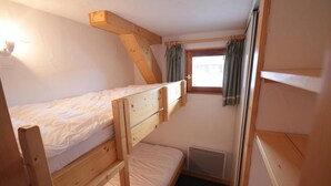Een kleine kamer met een enkel bed, schuine wanden en houten balken.
