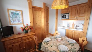 Een gezellige keuken met houten kastjes, een eettafel gedekt voor vier personen, en een magnetron.
