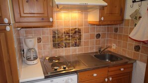 Una cocina compacta con una cafetera Bosch, estufa y lavavajillas.