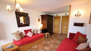 Una habitación acogedora con un sofá rojo, un banco de madera, una mesita y un espejo en la pared.