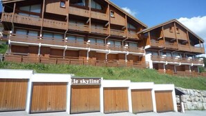 Un edificio de madera de varios pisos con balcones, un letrero que dice "le skyline" y un muro de piedra en primer plano.