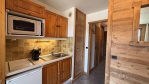 A kitchen with wooden cabinets, a microwave, a sink, and a Bosch refrigerator. - 200m from ski slopes, 1st floor, view ski slopes, balcony, tv, ski locker, 24m², Les Saisies (Les Saisies)