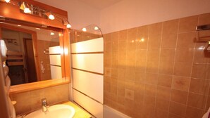 Une salle de bain avec un lavabo, un miroir et des murs carrelés.