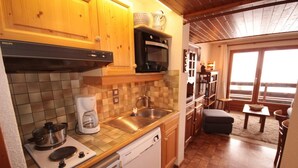 A compact kitchen with wooden cabinets, a coffee maker, a microwave, and a dishwasher. - 100m from ski slopes, 1st floor, view ski slopes, balcony, tv, ski locker, 26m², Les Saisies (Les Saisies)