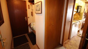 A narrow hallway with wooden doors leading to a kitchen area. - 100m from ski slopes, 1st floor, view ski slopes, balcony, tv, ski locker, 26m², Les Saisies (Les Saisies)