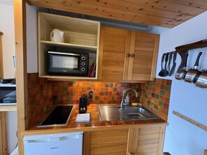 A compact kitchen with a microwave, sink, and wooden cabinets.