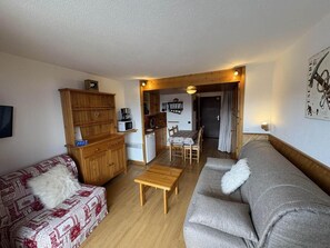 A compact living space with a kitchenette, a dining area, and a sofa.