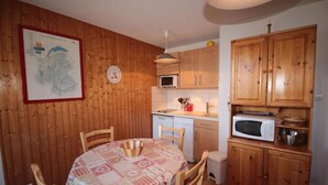A compact kitchen with wooden cabinets, a microwave, and a dining table with chairs. - 250m from ski slopes, 1st floor, view mountain, balcony, tv, 28m², Les Saisies (Les Saisies)
