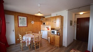 A compact kitchen with wooden cabinets, a microwave, and a dining area with a table and chairs. - 250m from ski slopes, 1st floor, view mountain, balcony, tv, 28m², Les Saisies (Les Saisies)