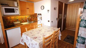 Una cocina compacta con armarios de madera, un microondas, un fregadero y una mesa de comedor con sillas.