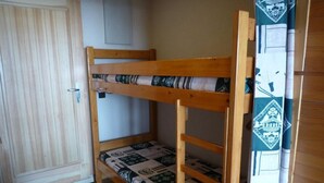 Una litera con colchón estampado, una puerta de madera y una cortina con diseño geométrico.