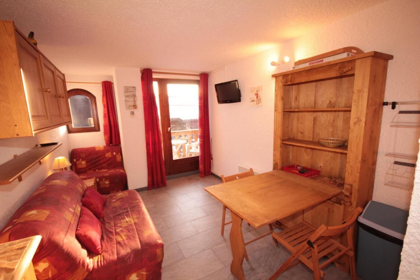 Ein gemütlicher Wohnbereich mit einer Couch, einem Holztisch und einer kleinen Küchenzeile.