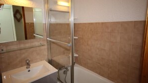 Un baño con cabina de ducha de vidrio, un lavamanos y una bañera.