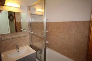 Un bagno con box doccia in vetro, lavandino e vasca da bagno.