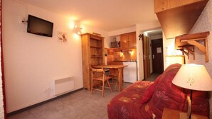 Un espacio habitable pequeño con kitchenette, comedor y sofá con lámpara.