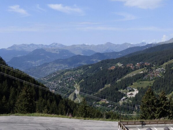 Paisagem montanhosa com um vale, casas e uma estrada.
