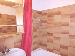 Un baño con lavamanos, espejo y zona de ducha.