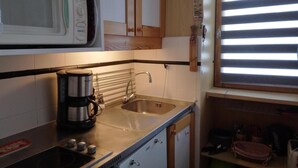 Une cuisine compacte équipée d’un four à micro-ondes, d’une machine à café et d’un évier.