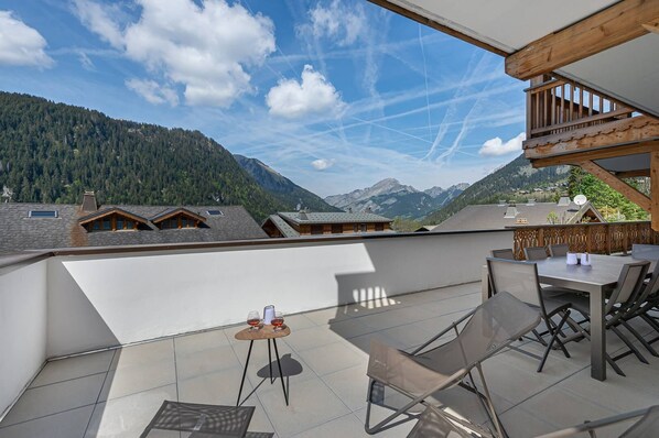 A terrace with a table and chairs, overlooking a mountainous landscape. - Close to the centre, new flat with 4 bedrooms and 3 bathrooms (CHATEL)
