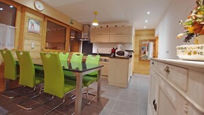 A modern kitchen with green chairs, a dining table, and wooden cabinets.