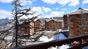 A mountain resort with multi-story buildings, a wooden fence, and snow-covered ground. - 100m from ski slopes, 3rd floor, view ski slopes, swimming pool, sauna, balcony, tv, ski locker (Risoul)