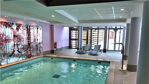 An indoor swimming pool with clear water, a large mural on the wall, and two lounge chairs. - 100m from ski slopes, 3rd floor, view ski slopes, swimming pool, sauna, balcony, tv, ski locker (Risoul)