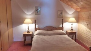 A bedroom with a wooden ceiling, a bed with a headboard, two bedside tables with lamps, and two wall-mounted pictures. - 30m from ski slopes, 3rd floor, view mountain, balcony, tv, ski locker, 58m², Méribel (Méribel - Les Allues)