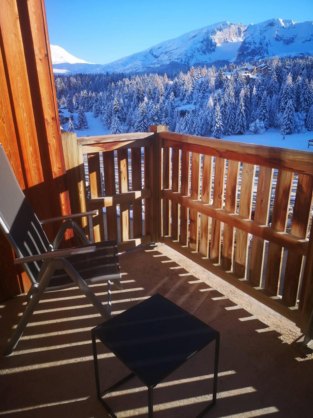 Ein Holzbalkon mit Blick auf einen schneebedeckten Berg und Wald.