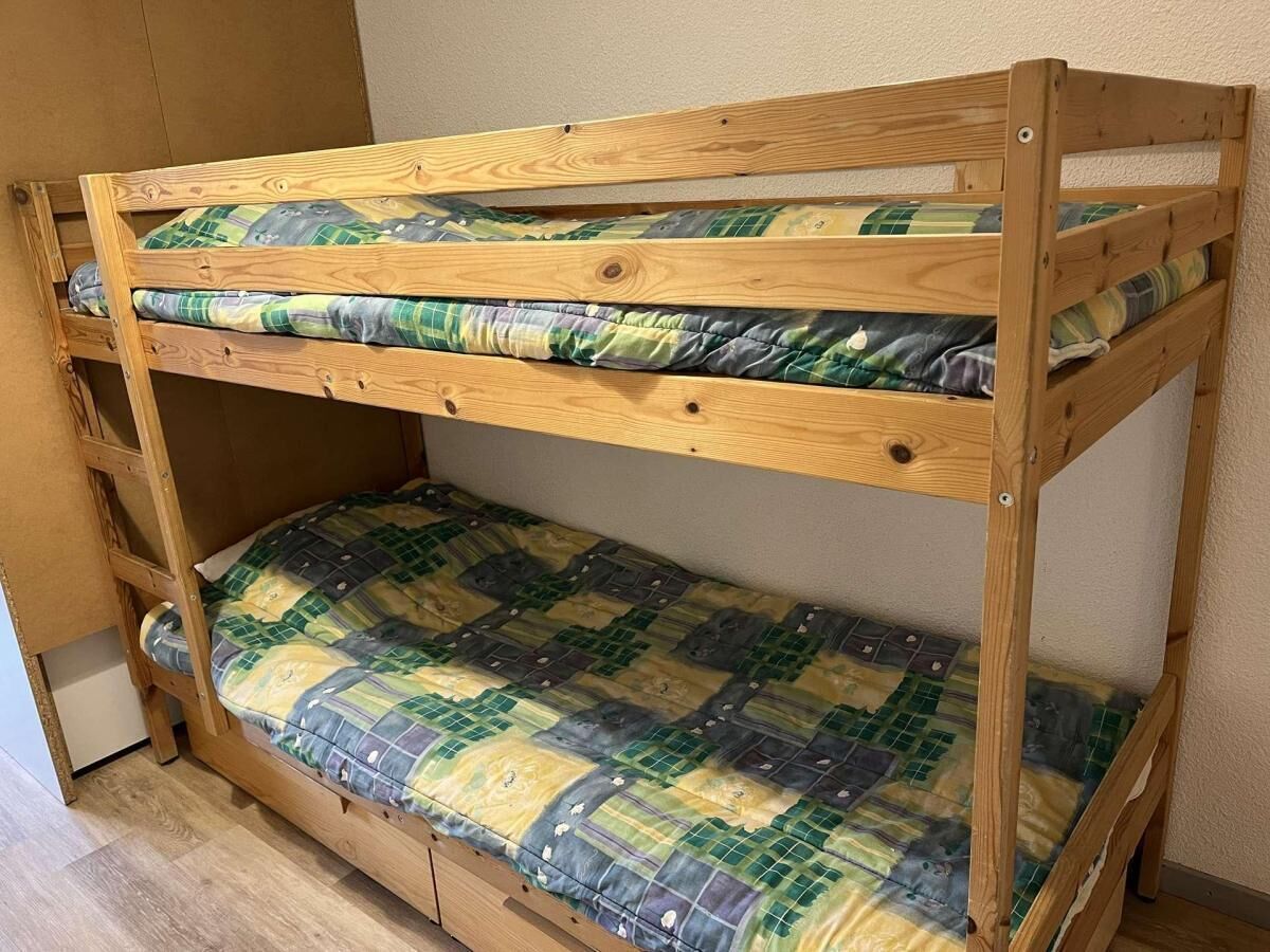 A bunk bed with two levels, each with a quilted mattress.