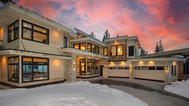 Ein modernes, mehrstöckiges Haus mit großen Fenstern und einer Garage, umgeben von Schnee.