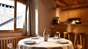 A dining area with a round table set for two, a vase, and a window with curtains. - 100m from ski slopes, 4th floor, balcony, ski locker, 60m², Méribel (Méribel - Les Allues)