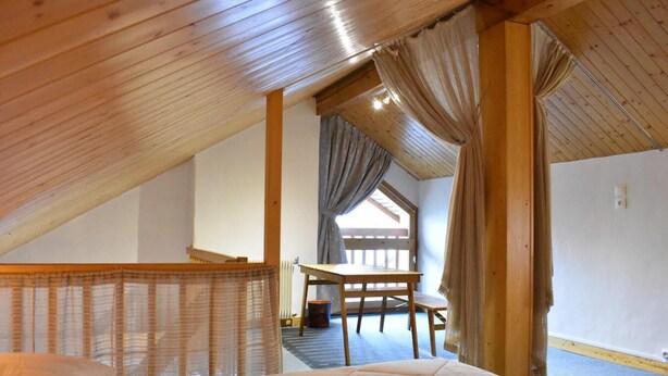 A bedroom with a wooden ceiling, a bed, a table, and a chair. - 100m from ski slopes, 4th floor, balcony, ski locker, 60m², Méribel (Méribel - Les Allues)
