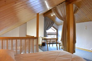 Un dormitorio con techo de madera, una cama, una mesa y una silla.