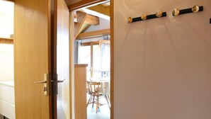 A wooden door leading to a room with a window, a chair, and a wall-mounted light fixture. - 100m from ski slopes, 4th floor, balcony, ski locker, 60m², Méribel (Méribel - Les Allues)
