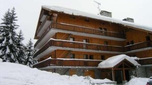 A multi-story wooden building with balconies, surrounded by snow-covered trees. - 100m from ski slopes, 4th floor, balcony, ski locker, 60m², Méribel (Méribel - Les Allues)