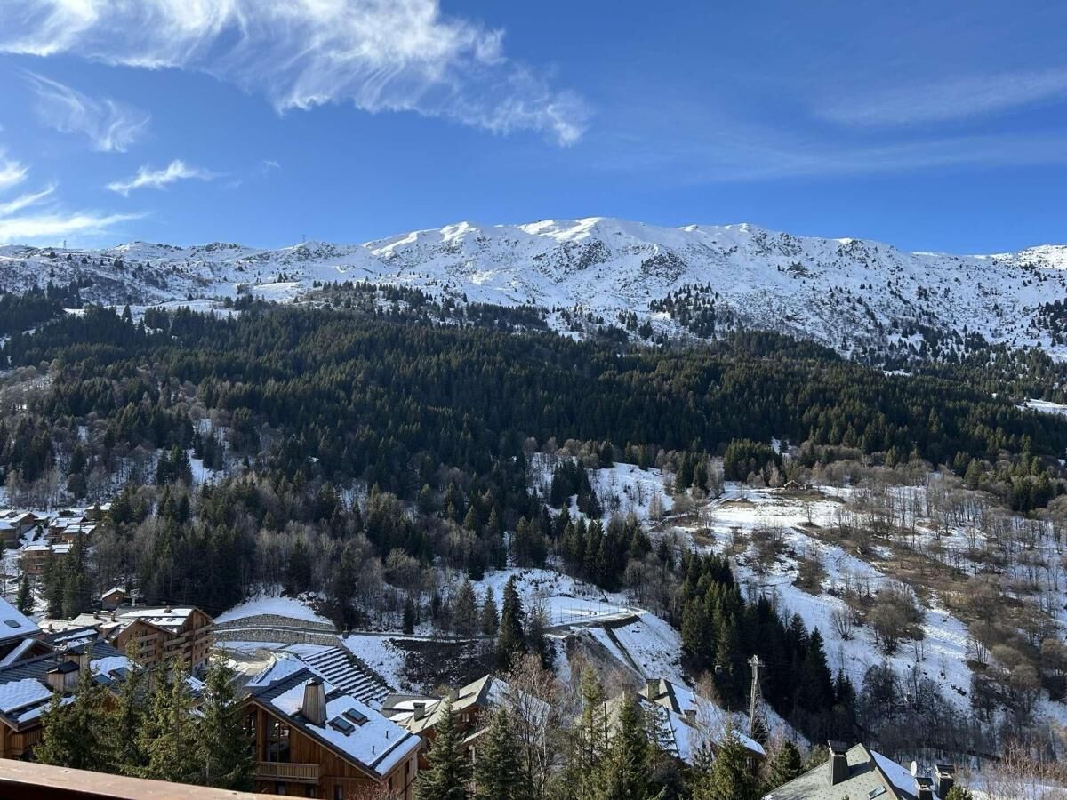A mountain landscape with snow-covered peaks and a forested valley.