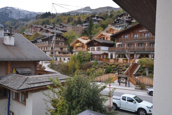 A mountain village with traditional wooden buildings, including a hotel with a balcony and a staircase leading to the upper floors.