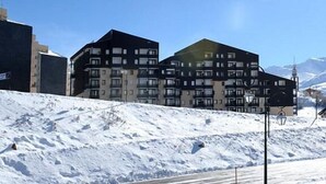 A modern building with multiple floors, surrounded by a snowy landscape. - Ski-in/ski-out & foot of the slopes, 5th floor, balcony, tv, 27m², Les Menuires (Les Menuires)